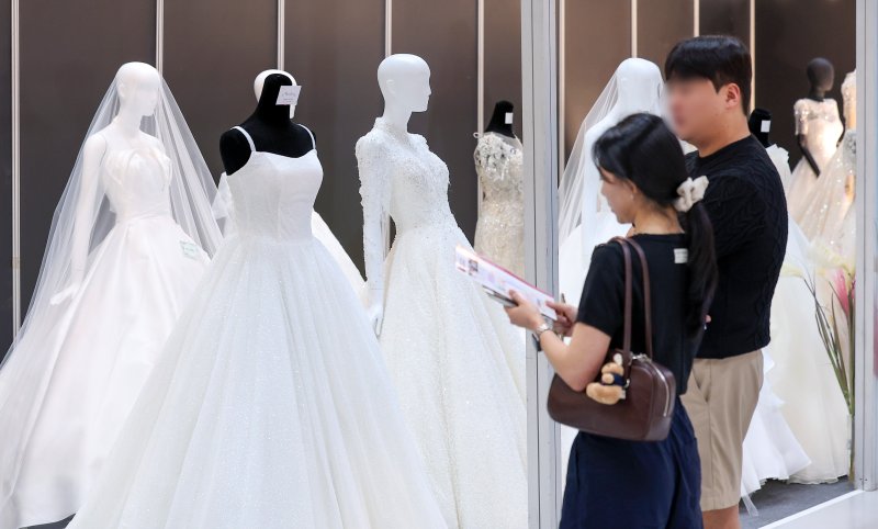 서울 강남구 삼성동 코엑스에서 열린 2025 추계 웨덱스 웨딩 박람회에서 예비 부부들이 전시된 드레스를 살펴보고 있다. 2025.7.6/뉴스1 ⓒ News1 김성진 기자