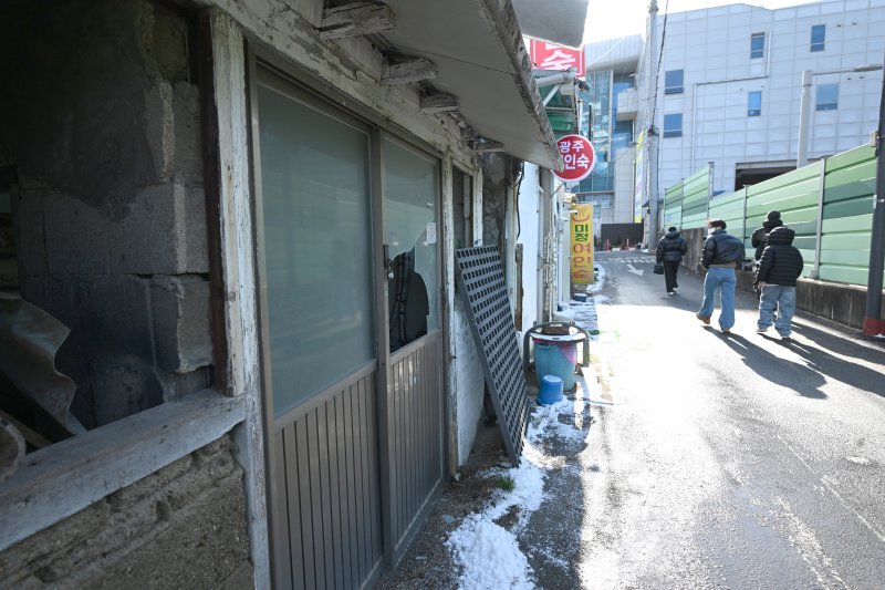 [광주=뉴시스] 이현행 기자 = 지난 26일 오후 광주 광산구 광주송정역 인근에서 시민들이 깨지고 부서진 폐건물과 여인숙을 쳐다보며 걷고 있다. 2025.12.30. lhh@newsis.com