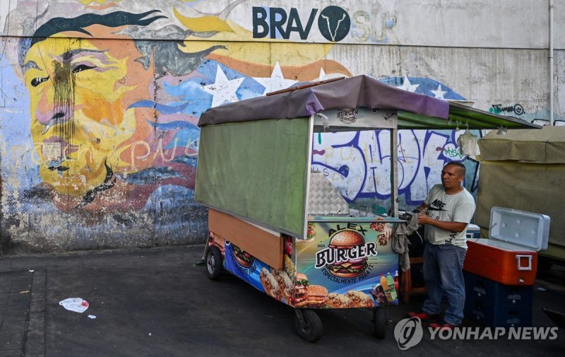 지난해 12월 29일(현지시간) 차베스 벽화 앞에서 햄버거 파는 상인 (출처=연합뉴스)