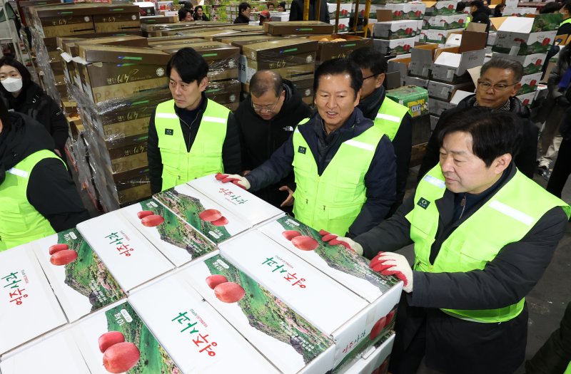 [서울=뉴시스] 조성우 기자 = 정청래(왼쪽 세 번째) 더불어민주당 대표가 7일 오전 서울 송파구 가락동 농수산물 종합도매시장 중앙청과에서 경매를 마친 사과 상자를 운반차에 싣고 있다. 2026.01.07. xconfind@newsis.com