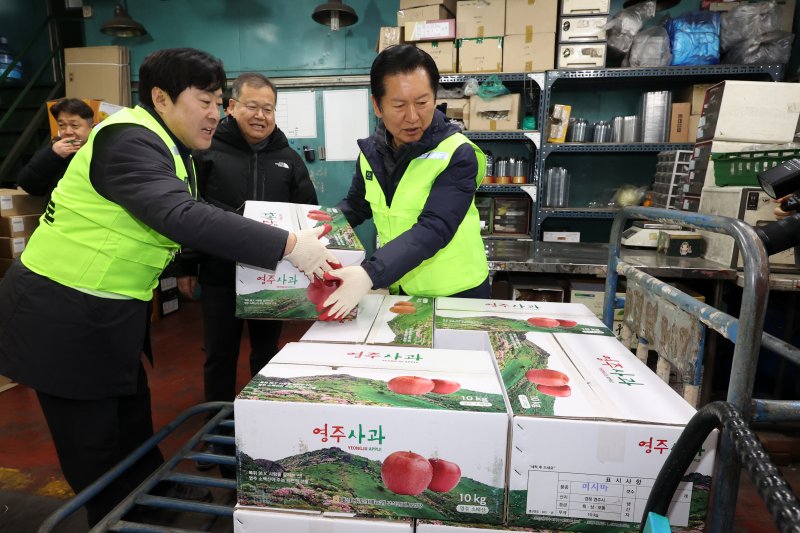 [서울=뉴시스] 조성우 기자 = 정청래(오른쪽) 더불어민주당 대표와 황명선 최고위원이 7일 오전 서울 송파구 가락동 농수산물 종합도매시장 중앙청과에서 경매를 마친 사과 상자를 옮기고 있다. 2026.01.07. xconfind@newsis.com
