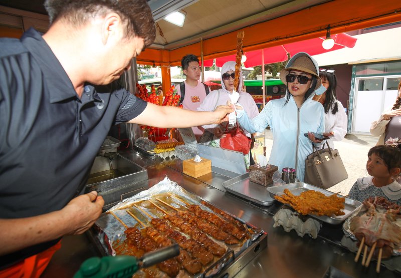 [제주=뉴시스] 우장호 기자 = 중국인 단체관광객(유커·遊客)들이 31일 오후 제주 시내권 대표적인 관광지인 용두암을 찾아 우리나라 간식을 체험하고 있다. 2017년 '한한령(한류제한령)' 이후 6년5개월 만에 크루즈선 '블루드림스타호(Blue Dream Star·2만4782t)를 타고 온 이들은 8시간 가량 제주에 머문 후 일본으로 향한다. 2023.08.31. woo1223@newsis.com