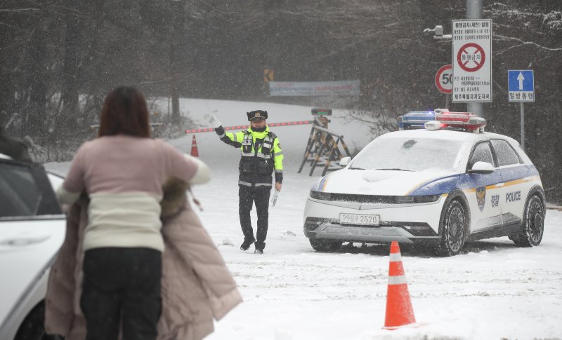 [제주=뉴시스] 우장호 기자 = 제주 산지·중산간·동부·남부에 대설특보가 내려진 11일 오전 제주시 어승생 삼거리 입구에서 제주서부경찰서 소속 경찰관이 도로통제를 하고 있다. 기상청에 따르면 제주도는 12일까지 한라산 등 고지대를 중심으로 최대 15㎝의 눈이 내려 쌓일 것으로 예측됐다. 2026.01.11. woo1223@newsis.com