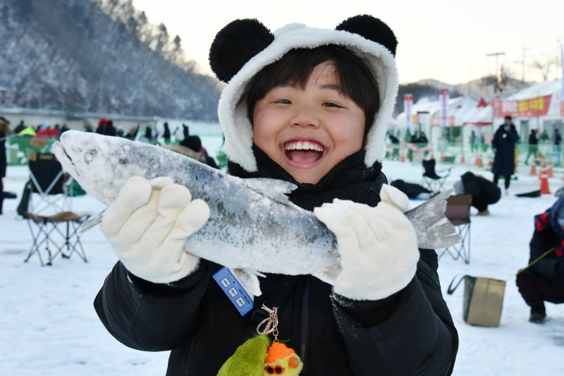 한 어린이가 직접 잡은 산천어를 들어보이며 기뻐하고 있다.