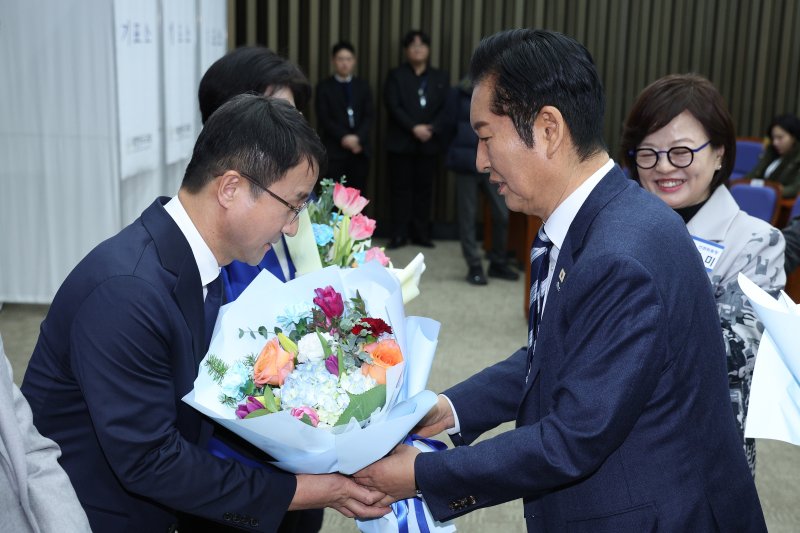 한병도 더불어민주당 신임 원내대표가 11일 서울 여의도 국회에서 열린 제22대 국회 더불어민주당 원내대표 선출을 위한 의원총회에서 정청래 대표로부터 꽃다발을 받고 있다. 2026.1.11/뉴스1 ⓒ News1 신웅수 기자