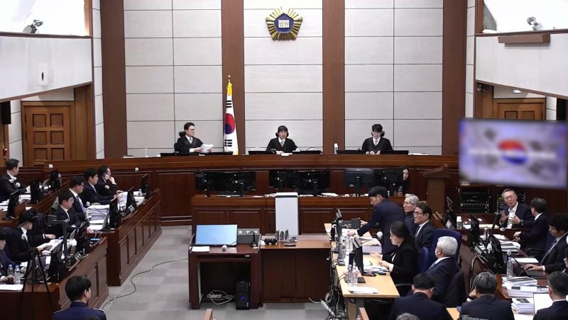 윤석열 전 대통령이 13일 오후 서울 서초구 서울중앙지방법원에서 진행된 내란 우두머리 혐의 2차 결심공판에 출석해 자리에 앉아 윤갑급 변호사와 대화를 하고 있다. (서울중앙지방법원 제공 영상 캡쳐. 재판매 및 DB 금지) 2026.1.13/뉴스1