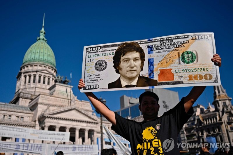 미국 100달러 지폐 디자인에 밀레이 대통령 얼굴을 합성해 만든 플래카드 든 아르헨티나 주민 (출처=연합뉴스)