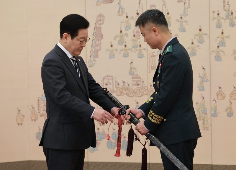 이재명 대통령이 16일 청와대 본관에서 열린 3성 장군 진급·보직 신고 및 수치 수여식에서 박성제 육군특수전사령부 사령관의 삼정검에 수치를 달아주고 있다. 뉴시스