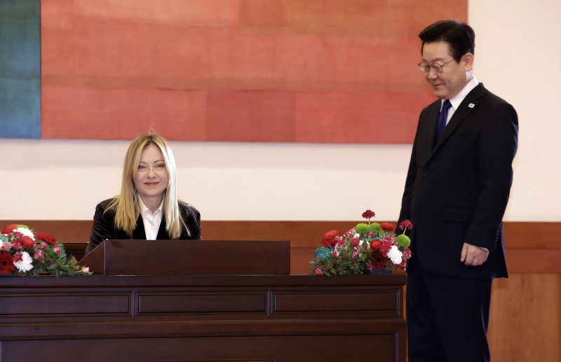 이재명 대통령이 19일 청와대에서 방명록을 작성하는 조르자 멜로니 이탈리아 총리를 지켜보고 있다. 청와대통신사진기자단