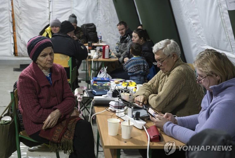 거리의 비상 대피 텐트에서 추위 피하며 스마트폰 충전하는 키이우 시민들 (출처=연합뉴스)