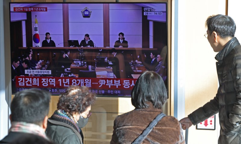 28일 오후 서울역 대합실에서 시민들이 김건희 여사의 자본시장법·정치자금법 위반, 특정범죄 가중처벌법상 알선수재 혐의 1심 선고 공판 생중계를 지켜보고 있다. 서울중앙지법 형사합의27부(부장판사 우인성)는 이날 알선수재 등 혐의로 기소된 김 여사에게 징역 1년 8개월을 선고했다. 압수된 그라프사 다이아몬드 목걸이의 몰수 및 1281만 원의 추징도 명했다. 자본시장법 위반과 정치자금법 위반 혐의에 대해서는 무죄를 선고했다. 2026.1.28/뉴스1 ⓒ News1 오대일 기자