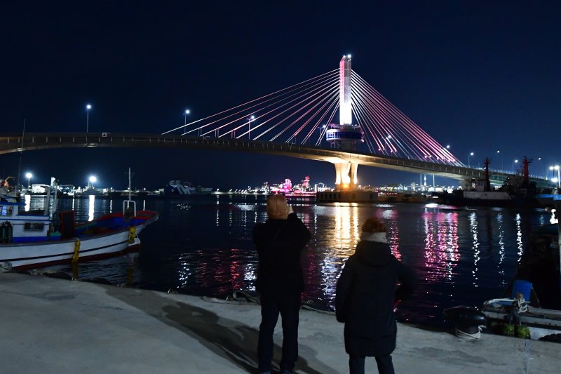 31일 경북 포항시 송도동(송도해수욕장)과 항구동(영일대해수욕장)을 연결하는 해오름대교에서 경관조명이 붉을 밝히자 시민들이 휴대폰으로 촬영하고 있다. 2026.1.31/뉴스1 ⓒ News1 최창호 기자