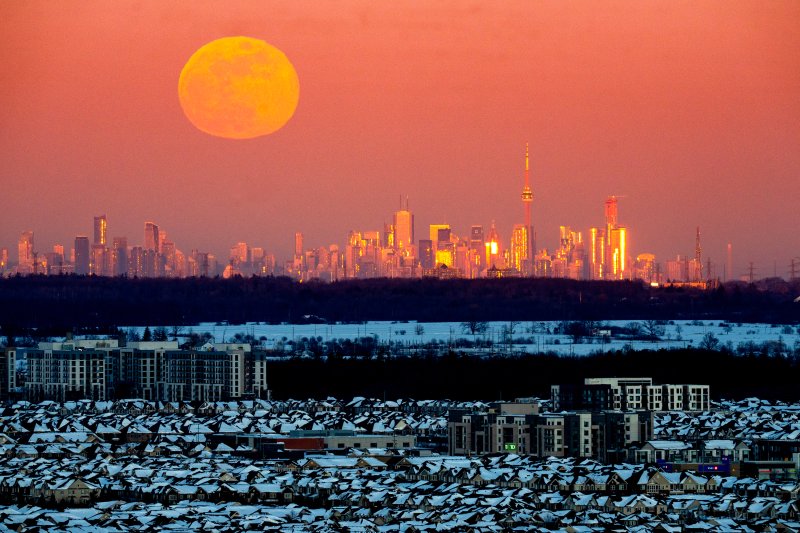 [토론토=AP/뉴시스] 1일(현지 시간) 캐나다 토론토 스카이라인이 석양에 붉게 물든 가운데 보름달이 떠오르고 있다. 2월 보름달은 슈퍼문은 아니며 전통적으로 눈이 많이 내리는 시기에 뜬다고 해서 ‘스노우문(Snow Moon)’이라고도 부른다. 2026.02.02.
