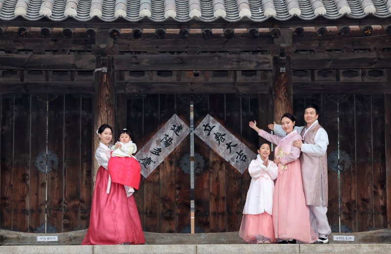 [서울=뉴시스] 조성우 기자 = 절기상 입춘인 4일 오전 서울 중구 남산골한옥마을에서 열린 입춘첩 붙이기 시연 행사에 참여한 1990년생 경오년 말띠인 박민지(왼쪽) 씨와 박은혜 씨가 가족과 함께 '입춘대길·건양다경'이라고 적힌 입춘첩을 붙인 뒤 포즈를 취하고 있다. 2026.02.04. xconfind@newsis.com