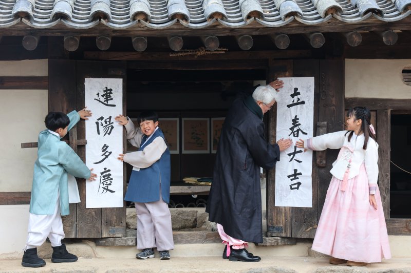 봄의 시작을 알리는 입춘(立春)인 4일 서울 종로구 삼청동 국립민속박물관내 전통한옥인 오촌댁 대문에 어린이들이 '입춘대길(立春大吉)'과 '건양다경(建陽多慶)' 글귀를 담은 입춘첩을 붙이고 있다. 2026.2.4/뉴스1 ⓒ News1 이광호 기자