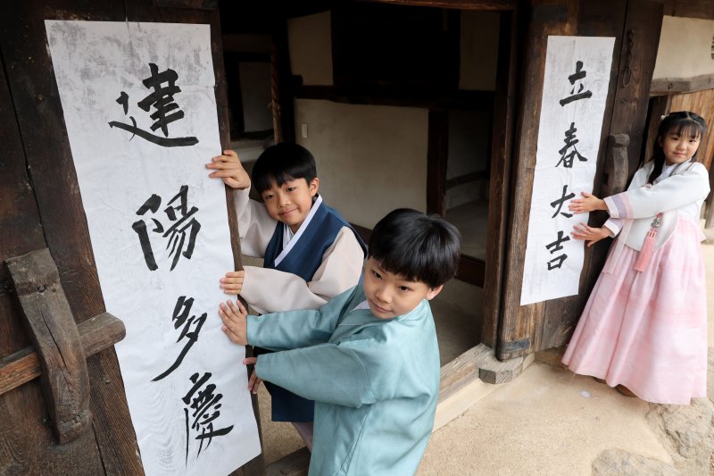 봄의 시작을 알리는 입춘(立春)인 4일 서울 종로구 삼청동 국립민속박물관내 전통한옥인 오촌댁 대문에 어린이들이 '입춘대길(立春大吉)'과 '건양다경(建陽多慶)' 글귀를 담은 입춘첩을 붙이고 있다. 2026.2.4/뉴스1 ⓒ News1 이광호 기자