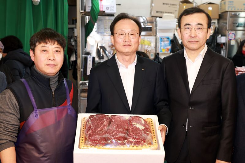 KB국민은행은 11일 서울 마포구 망원시장에서 설 명절을 앞두고 '전통시장 사랑나눔' 행사를 진행했다. 이세훈 금융감독원 수석부원장(왼쪽)과 이환주 KB국민은행장(가운데)이 식료품을 구입한 후 기념촬영을 하고 있다. KB국민은행 제공