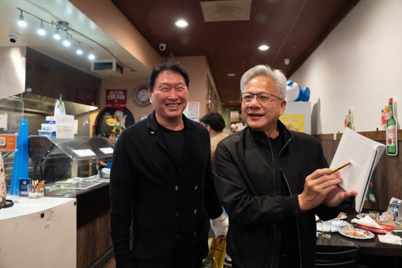 최태원 SK그룹 회장(왼쪽)이 지난 5일(현지시간) 미국 캘리포니아 산타클라라의 한국식 호프집 '99치킨'에서 젠슨 황 엔비디아 최고경영자(CEO)와 만찬 회동을 하며, SK하이닉스 성공기를 담은 신간 '슈퍼모멘텀'을 전달했다. 최 회장은 책에서 황 CEO에 대해 "타이밍을 아는 탁월한 승부사이자, 협상가"라고 칭했다. 황 CEO가 자신의 얘기가 담긴 페이지를 펼쳐보이고 있다. 연합뉴스