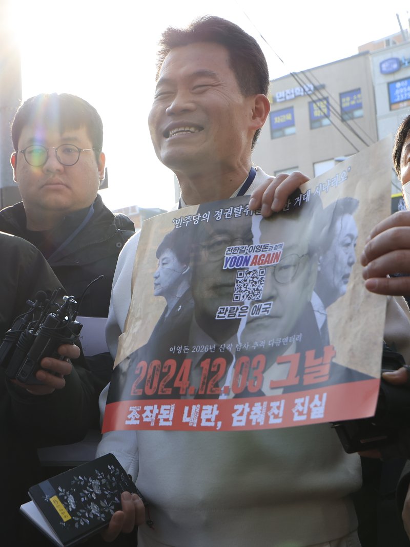 이재명 대통령과 김현지 청와대제1부속실장에 대한 허위 사실을 유포한 혐의로 고발된 한국사 강사 출신 보수 유튜버 전한길 씨가 12일 오전 서울시 동작구 노량진역 앞에서 피의자 신분 경찰 첫 소환 조사 출석에 앞서 입장을 밝히며 자신이 제작한 영화 포스터를 들어 보이고 있다. 2026.2.12 ⓒ 뉴스1 박정호 기자