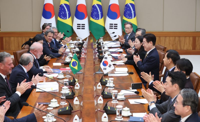 이재명 대통령이 23일 청와대에서 열린 한-브라질 확대정상회담에서 룰라 브라질 대통령 요청으로 책에 사인해 전달한 뒤 박수치고 있다. 연합뉴스