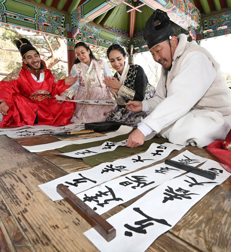 [용인=뉴시스] 김종택 기자 = 절기상 입춘을 이틀 앞둔 2일 경기 용인시 한국민속촌에서 외국인 관광객들이 입춘첩 작성을 살펴보고 있다. '입춘대길 건양다경(立春大吉 建陽多慶)'은 '봄이 시작되니 크게 길하고 경사스러운 일이 많이 생기길 기원한다'는 의미를 갖고 있다. 2026.02.02. jtk@newsis.com