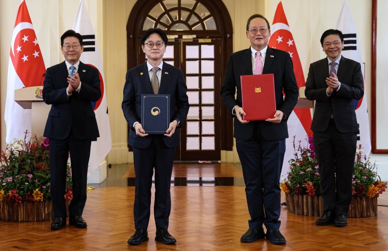 김정관 산업통상부 장관과 탄시렝 통상산업부 에너지·과학기술 담당 장관이 2일 싱가포르 외교부에서 이재명 대통령과 로렌스 웡 총리가 임석한 가운데 한-싱가포르 FTA 개선협상 개시 합의 선언문을 들고 기념촬영을 하고 있다. 뉴시스