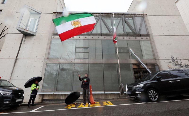 [서울=뉴시스] 조성우 기자 = 미국과 이스라엘의 이란 공습으로 아야톨라 알리 하메네이 최고지도자의 사망이 공식 확인된 가운데 2일 서울 용산구 주한 이란이슬람공화국 대사관 앞에서 한 이란인이 팔레비 왕조 시절 이란 국기를 흔들고 있다. 이란 정부는 지난 1일(현지 시간) 하메네이 최고지도자의 사망을 발표하며 40일간의 국가 애도 기간과 일주일간의 공휴일을 선포했다. 2026.03.02. xconfind@newsis.com