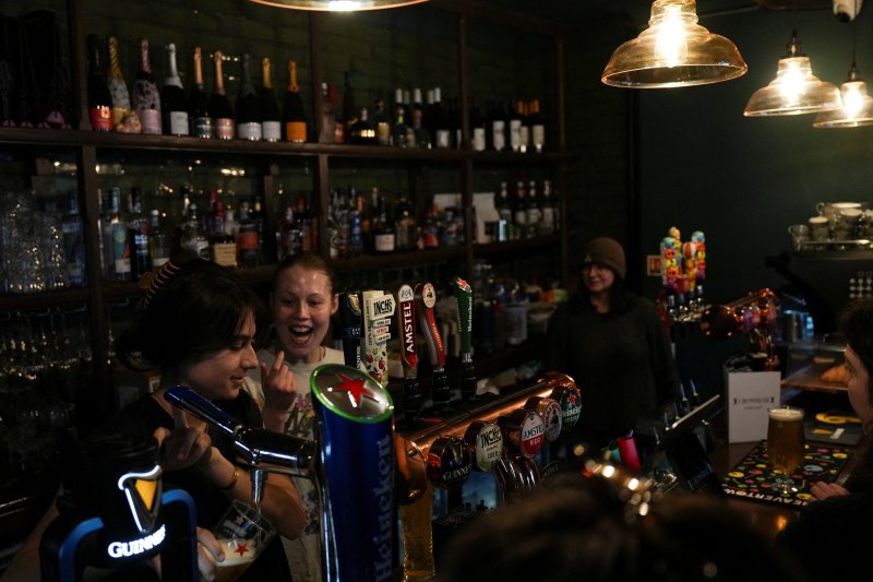 A bartender gestures to a colleague as she pours a craft beer while people watch a FIFA Women’s World Cup qualifiers match between Ukraine and England at Crossbar, Britain's first women’s sports bar, in Brighton, East Sussex, Britain, March 3, 2026. REUTERS/Carlos Jasso
