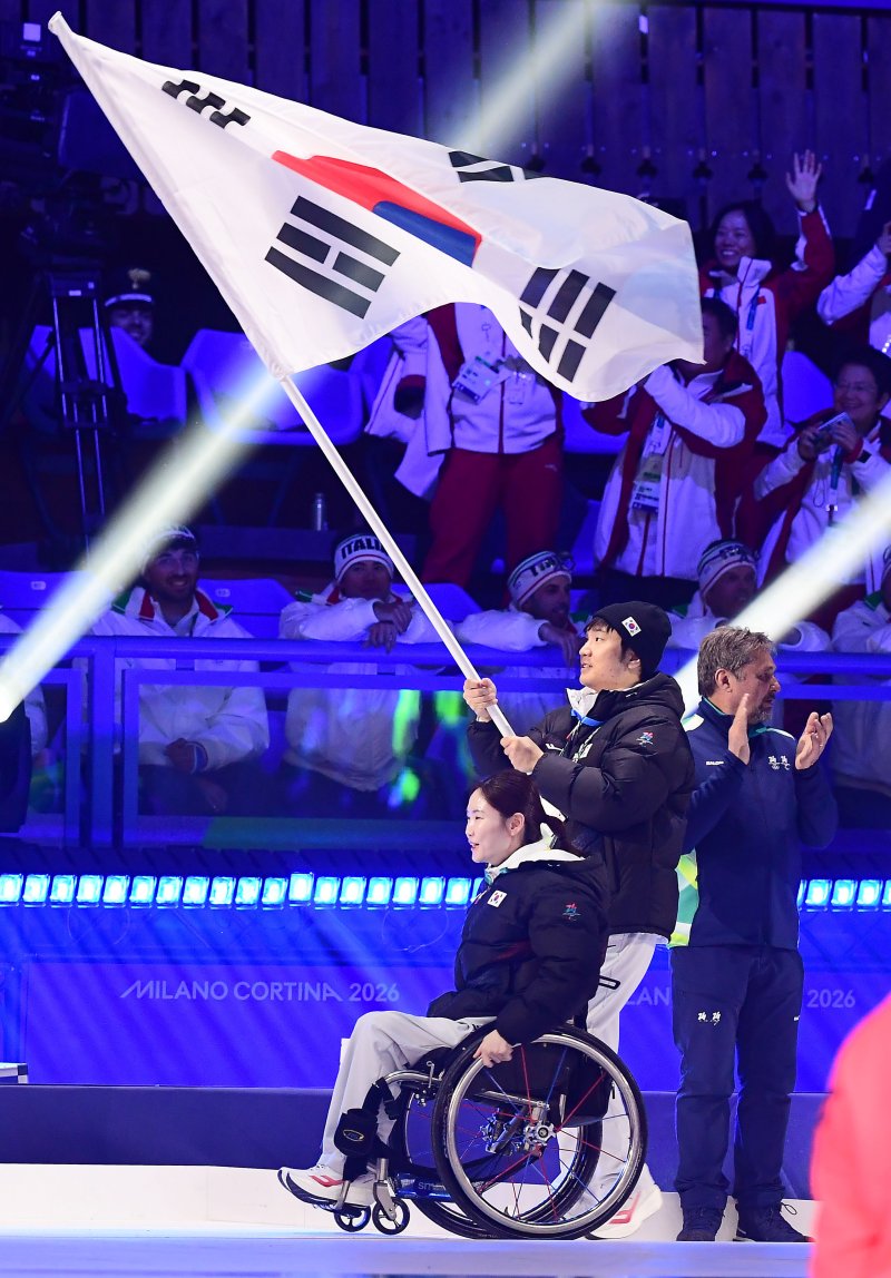 한국 선수단 기수 이제혁과 백혜진이 16일(한국시간) 열린 2026 밀라노·코르티나담페초 동계패럴림픽 폐회식에서 태극기를 들고 입장하고 있다. (대한장애인체육회 제공)