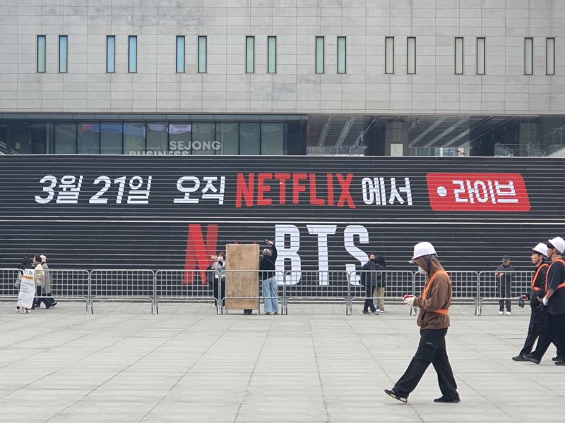 방탄소년단(BTS) 컴백 공연을 앞둔 지난 16일 서울 종로구 세종문화회관 앞 광화문광장에서 관광객들이 펜스 너머 BTS 조형물을 촬영하고 있다. 공연 무대 설치 작업이 진행되는 가운데 안전 펜스가 설치되면서 광장 일부 구간의 통행이 제한된 모습이다. 사진=최승한 기자