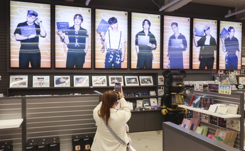 방탄소년단(BTS) 컴백 라이브: ARIRANG의 광화문 공연을 사흘 앞둔 지난 18일 오후 서울 중구 명동거리에 위치한 케이메카 명동본점에서 한 외국인이 사진을 찍고 있다. 뉴시스