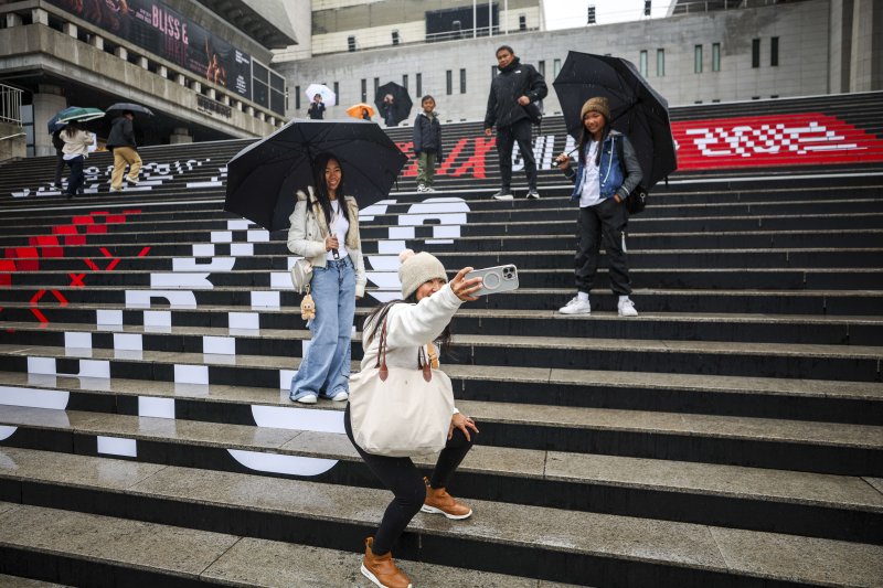 방탄소년단(BTS)의 서울 광화문광장 컴백 공연을 앞둔 지난 18일 서울 종로구 세종문화회관 계단을 찾은 외국인 팬들이 BTS 랩핑 앞에서 사진을 찍고 있다. 뉴시스