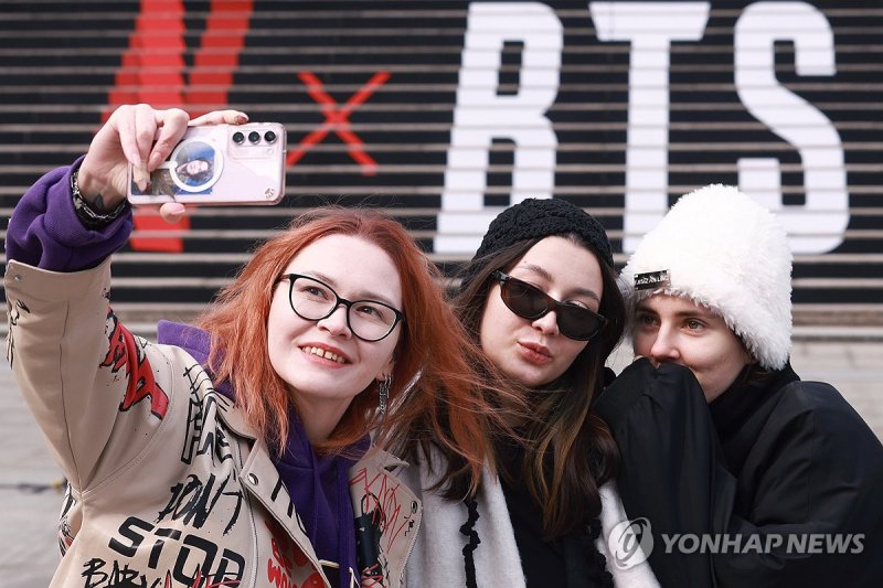 서울 종로구 세종문화회관 계단에서 방탄소년단(BTS) 공연 홍보물을 배경으로 기념촬영을 하는 관광객들. 연합뉴스