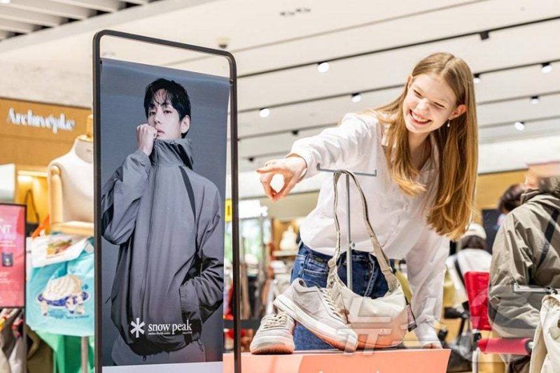 사진은 외국인 모델이 신세계면세점 명동점 K-패션 매장 앞에서 방탄소년단 멤버 뷔의 화보사진을 보는 모습. (신세계면세점 제공. 재판매 및 DB 금지) 2026.3.11 ⓒ 뉴스1