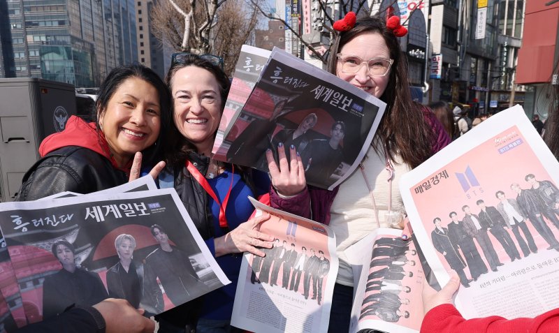 방탄소년단(BTS) 컴백 공연일인 21일 오전 서울 광화문광장 인근에서 외국인 관광객이 BTS 관련 특별판을 들고 기념촬영을 하고 있다. 2026.3.21 ⓒ 뉴스1 박지혜 기자