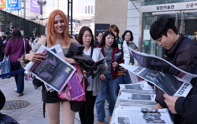 방탄소년단(BTS) 컴백 공연일인 21일 오전 서울 광화문광장에서 외국인 관광객이 주요 일간지들이 발행한 BTS 관련 특별판을 받고 있다. 2026.3.21 ⓒ 뉴스1 박지혜 기자
