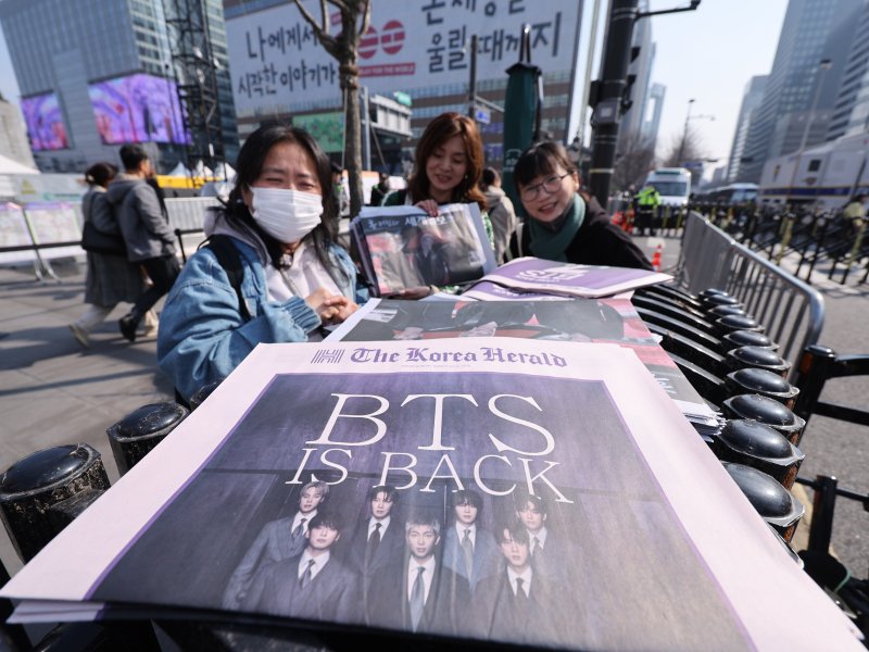 방탄소년단(BTS) 컴백 공연일인 21일 오전 서울 광화문광장에서 외국인 관광객이 주요 일간지들이 발행한 BTS 관련 호외를 받고 있다. 2026.3.21 ⓒ 뉴스1 박지혜 기자