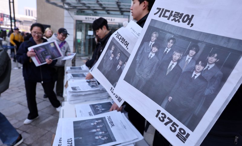 방탄소년단(BTS) 컴백 공연일인 21일 오전 서울 광화문광장에서 외국인 관광객이 일간지들이 발행한 BTS 관련 특별판을 무료로 배포받고 있다. 2026.3.21 ⓒ 뉴스1 박지혜 기자