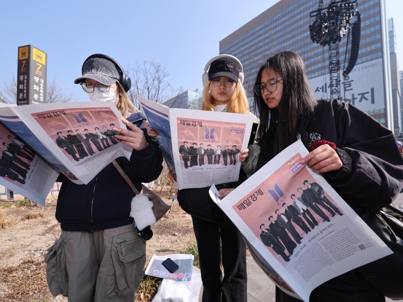 방탄소년단(BTS) 컴백 공연일인 21일 서울 종로구 광화문광장에서 외국인 관광객들이 주요 일간지들이 발행한 BTS 관련 특별판을 보고 있다. 2026.3.21 ⓒ 뉴스1 박지혜 기자