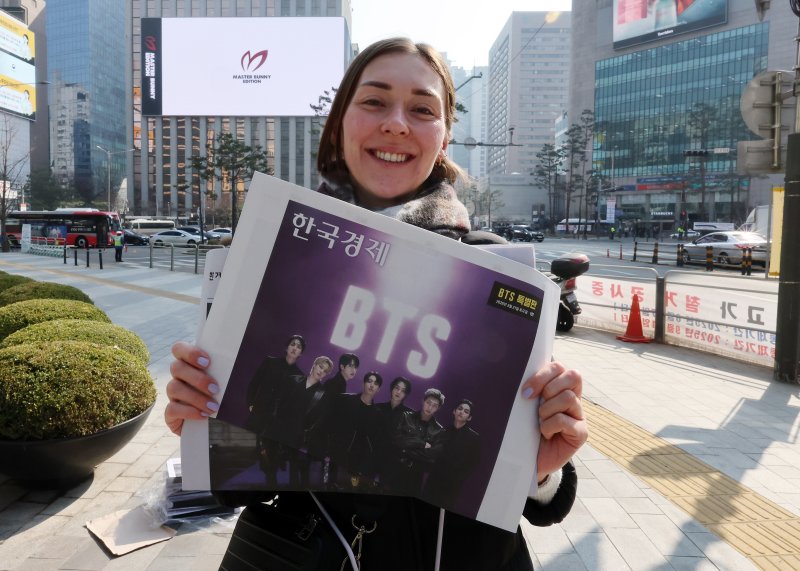 방탄소년단(BTS) 컴백 공연일인 21일 오전 서울 을지로입구역에서 독일인 관광객이 주요 일간지들이 발행한 BTS 특별판을 들어보이고 있다. 2026.3.21 ⓒ 뉴스1 김진환 기자