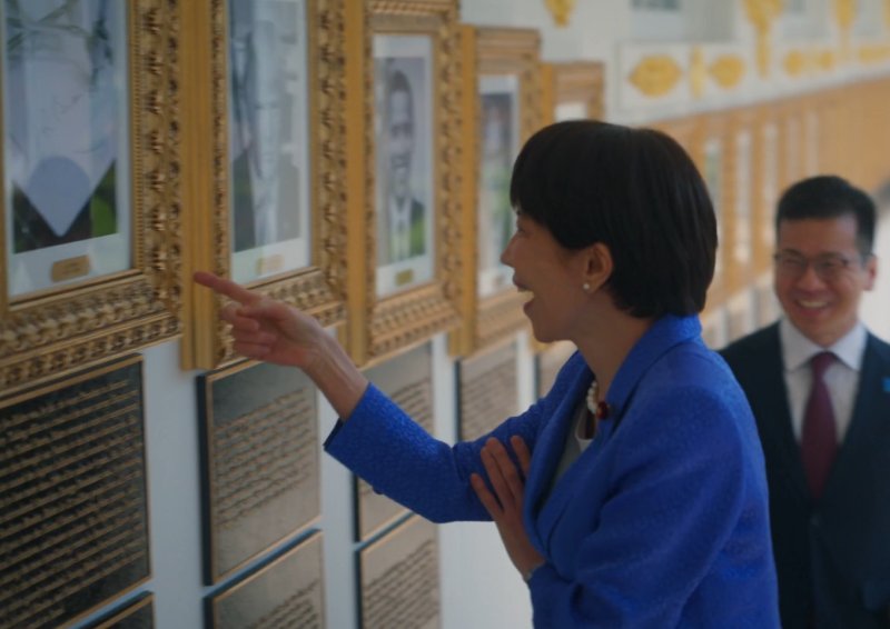 다카이치 사나에 일본 총리가 조 바이든 전 대통령의 초상화 자리에 그의 서명을 기계가 대신 그려주는 '오토펜' 사진이 걸려있는 것을 보고 웃음을 터뜨리고 있다. (백악관 X)