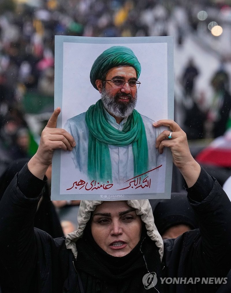 이란의 새 최고지도자 모즈타바 하메네이의 초상을 들고 있는 이란 여성. 모즈타바는 현재 공개석상에 나타나지 않고 행방이 묘연한 상태다. 연합뉴스