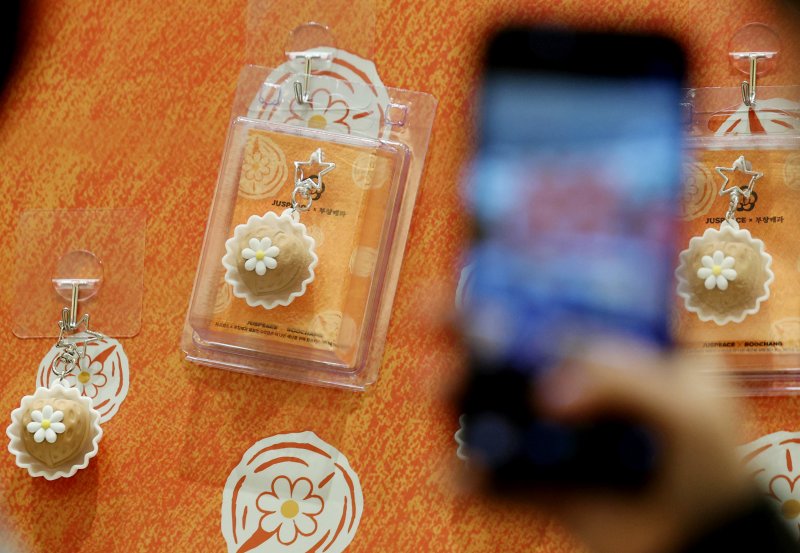 가수 지드래곤이 설립한 저스피스 재단과 80년 전통의 부창제과가 협업한 '데이지 밤(DAISY BOMB) 호두과자'가 정식 출시된 26일 서울 신세계 백화점 강남점 '스위트파크' 팝업스토어 부창제과에서 팬들이 제품 관련 굿즈를 촬영하고 있다. /사진=뉴시스