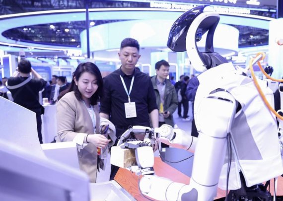 25일 중국 베이징 중관춘 전시센터 상설전에서 참가자들이 휴머노이드 로봇의 물품 집기 시연을 살펴보고 있다. CMG