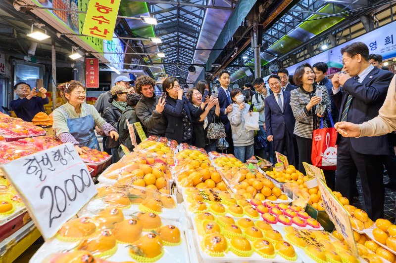 이재명 대통령이 30일 제주 타운홀 미팅을 마친 뒤 김혜경 여사와 함께 제주시 동문시장을 찾아 과일을 구매하고 있다. 청와대 제공