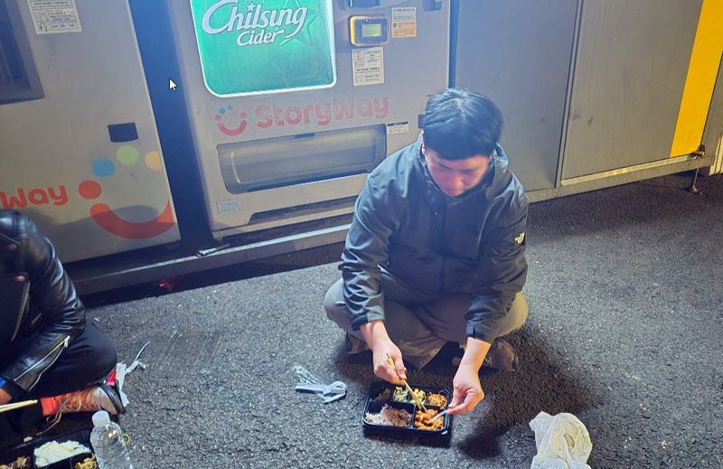 1일 오후 서울역 노숙인들 취재에 나선 기자가 무료 급식을 받아 아스팔트 위에서 식사를 하고 있다. 주변으로는 이날 친해진 노숙인들이 모여있다. 사진=한승곤 기자