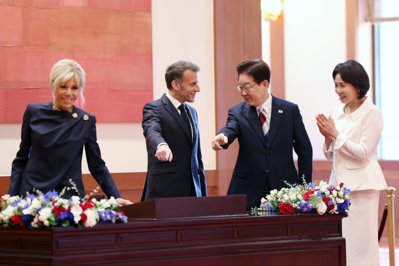 이재명 대통령이 3일 청와대에서 정상회담에 앞서 에마뉘엘 마크롱 프랑스 대통령과 방명록을 보며 대화를 나누고 있다. 뉴스1