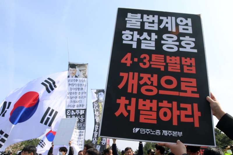 78주년 제주4·3희생자 추념식이 열리고 있는 3일 오전 제주시 봉개동 제주4·3평화공원 인근에서 민주노총 관계자들이 '불법 계엄 학살 옹호 4·3특별법 개정으로 처벌하라'는 팻말을 들고 있다. 이날 이곳에서는 추념식과 동시에 일부 극우단체 50여 명이 집회 신고를 했다.2026.4.3 ⓒ 뉴스1 홍수영 기자