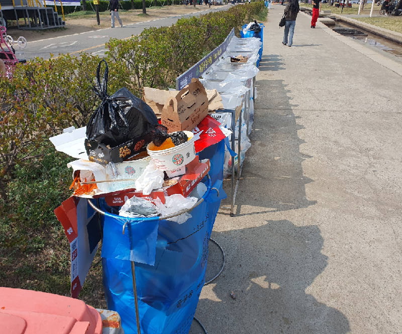 지난 3일 여의도 한강공원 산책로에 설치된 쓰레기통이 음식 용기와 포장재로 넘쳐나고 있다. 벚꽃축제 개막과 함께 방문객과 노점 이용이 늘면서 분리수거가 제대로 이뤄지지 않은 채 쓰레기가 방치된 모습. 사진=최승한 기자
