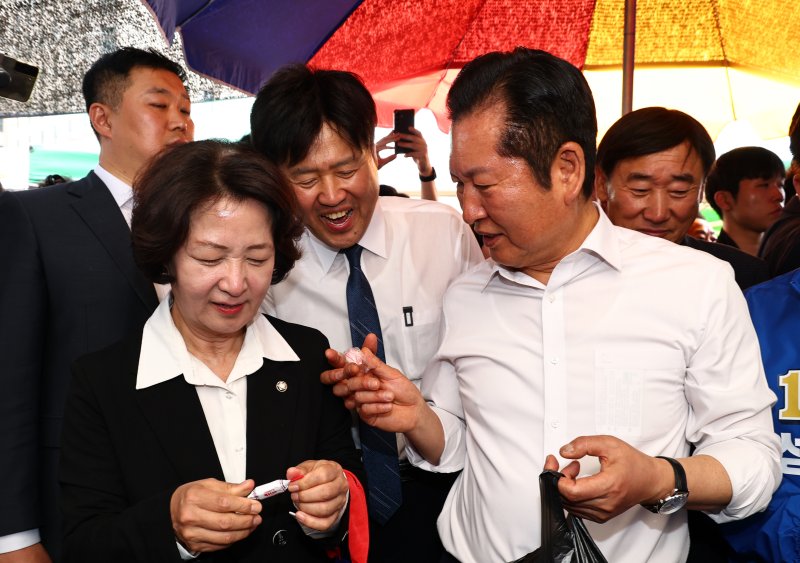 [서울=뉴시스] 김명년 기자 = 정청래 더불어민주당 대표가 19일 오후 경기 성남시 모란시장 민속5일장에서 김용 전 민주연구원 부원장에게 사탕을 건네고 있다. 2026.04.19. kmn@newsis.com